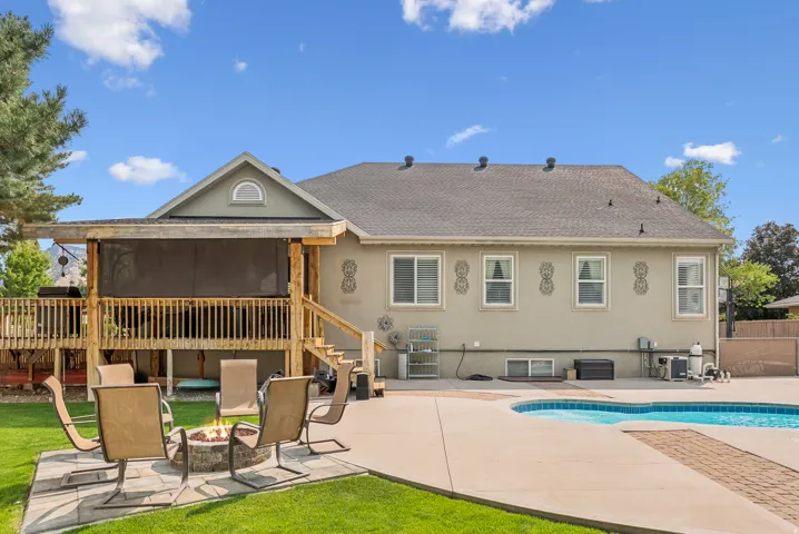 Rear view of house with a patio area, stucco siding, a sunroom, and a fire pit