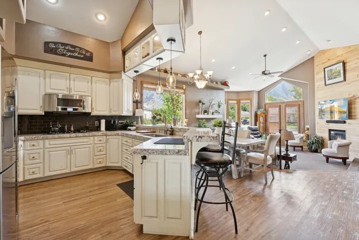 Kitchen with a peninsula, open floor plan, a breakfast bar area, light wood-style flooring, and a glass covered fireplace