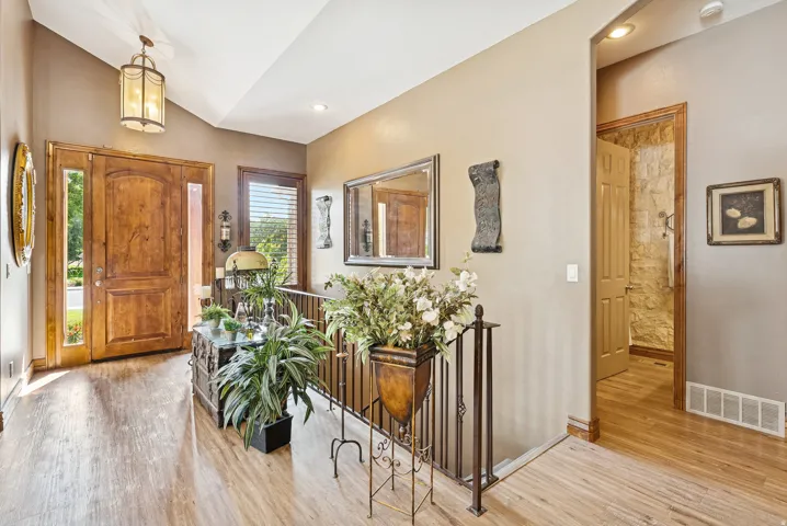 Entrance foyer with light wood-style flooring and vaulted ceiling