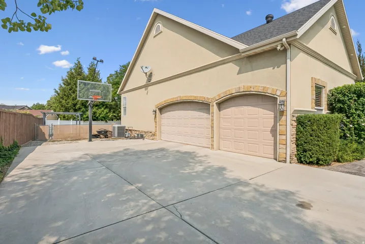 View of side of home featuring stone siding, stucco siding, driveway, and an attached garage
