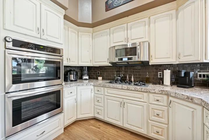 Kitchen with stainless steel appliances, light wood-type flooring, and backsplash