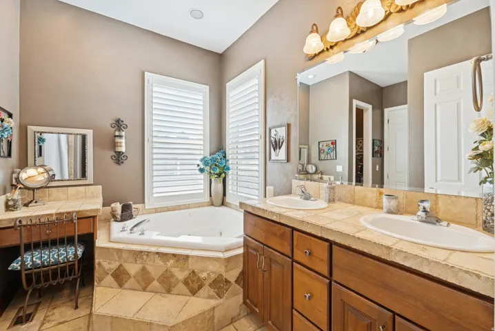 Bathroom featuring double vanity, a garden tub, and light stone finish flooring