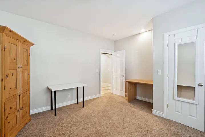 Unfurnished bedroom with light colored carpet and built in desk
