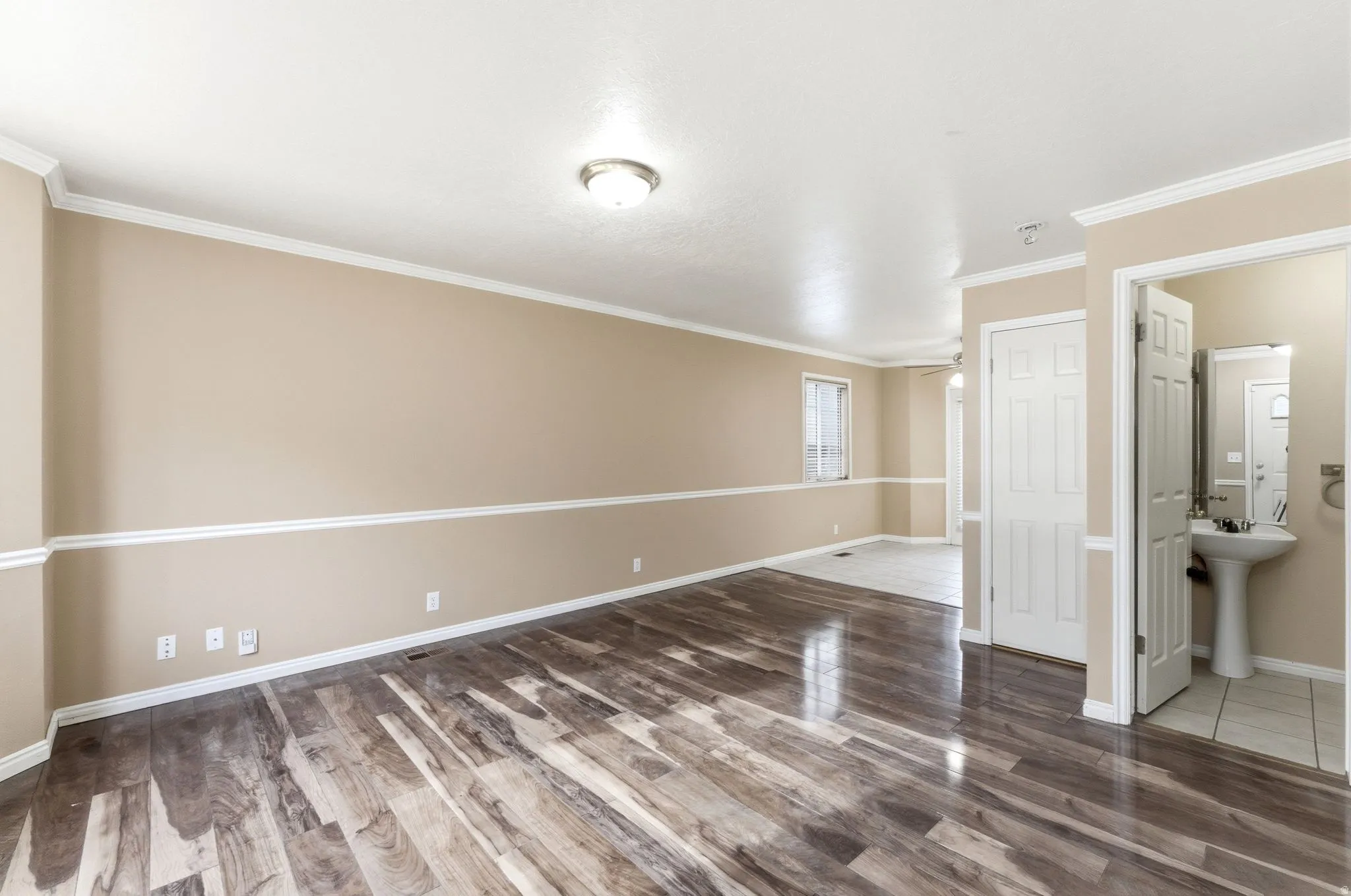 Empty room featuring light wood-style floors, ceiling fan, and ornamental molding