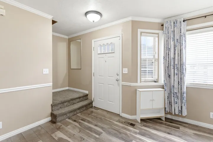 Entrance foyer with ornamental molding, light wood-type flooring, and a textured ceiling