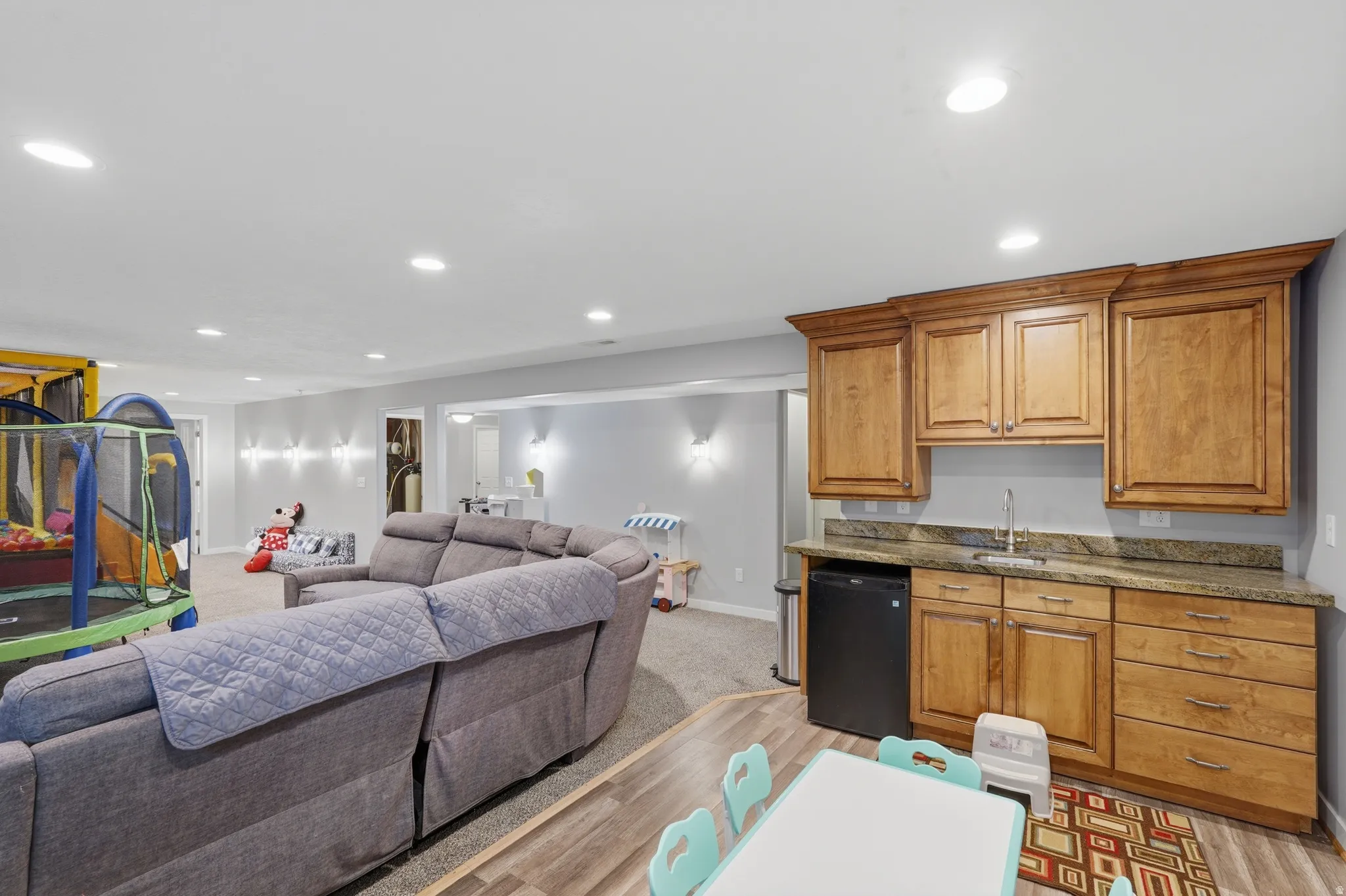 Kitchen with open floor plan, wood finish cabinets, dark stone countertops, light wood finished floors, and recessed lighting