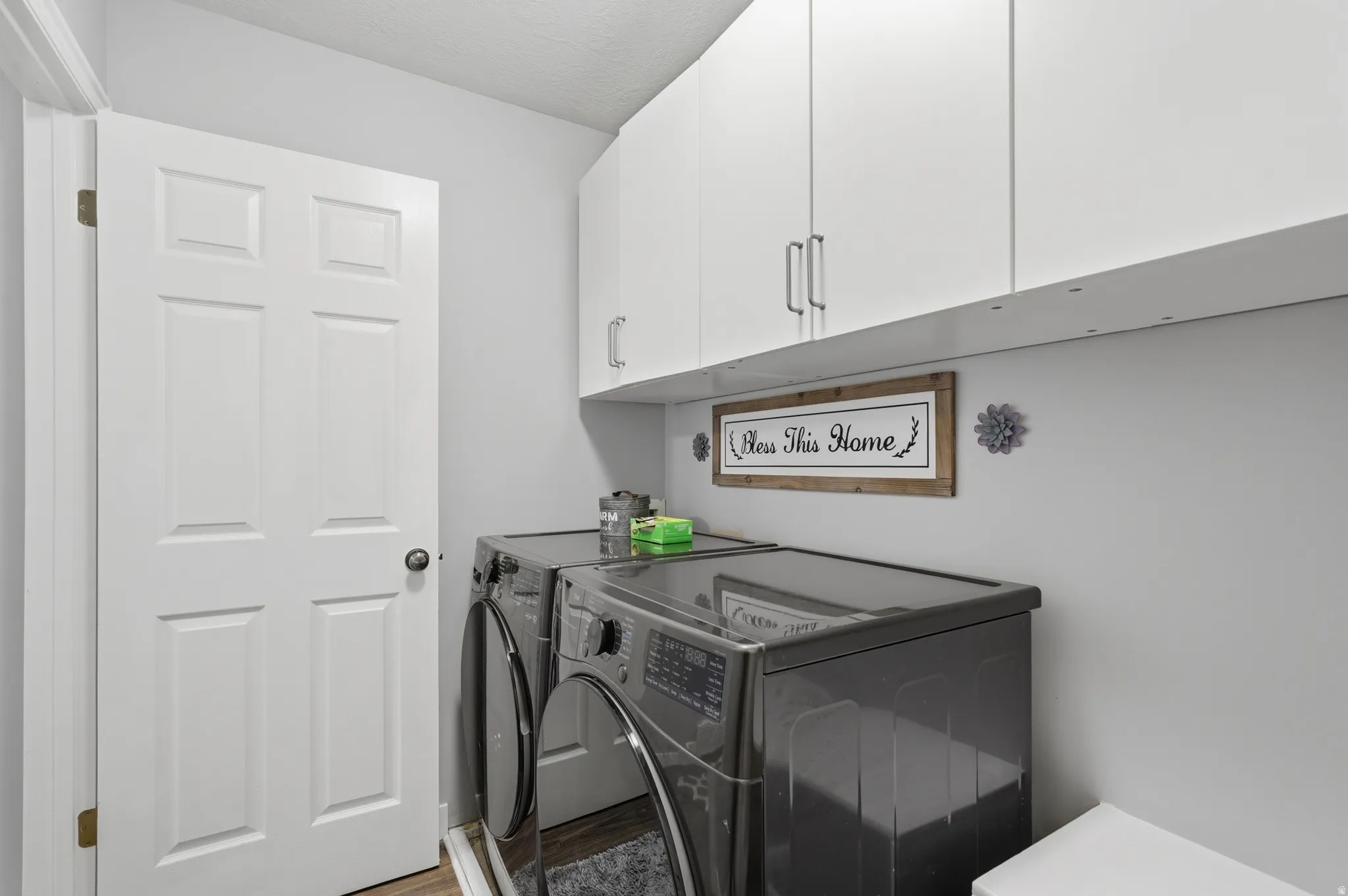Laundry room with washing machine and clothes dryer, cabinet space, and wood finished floors