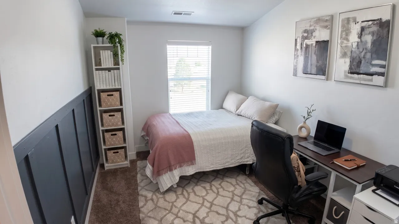 Bedroom with light colored carpet and a desk