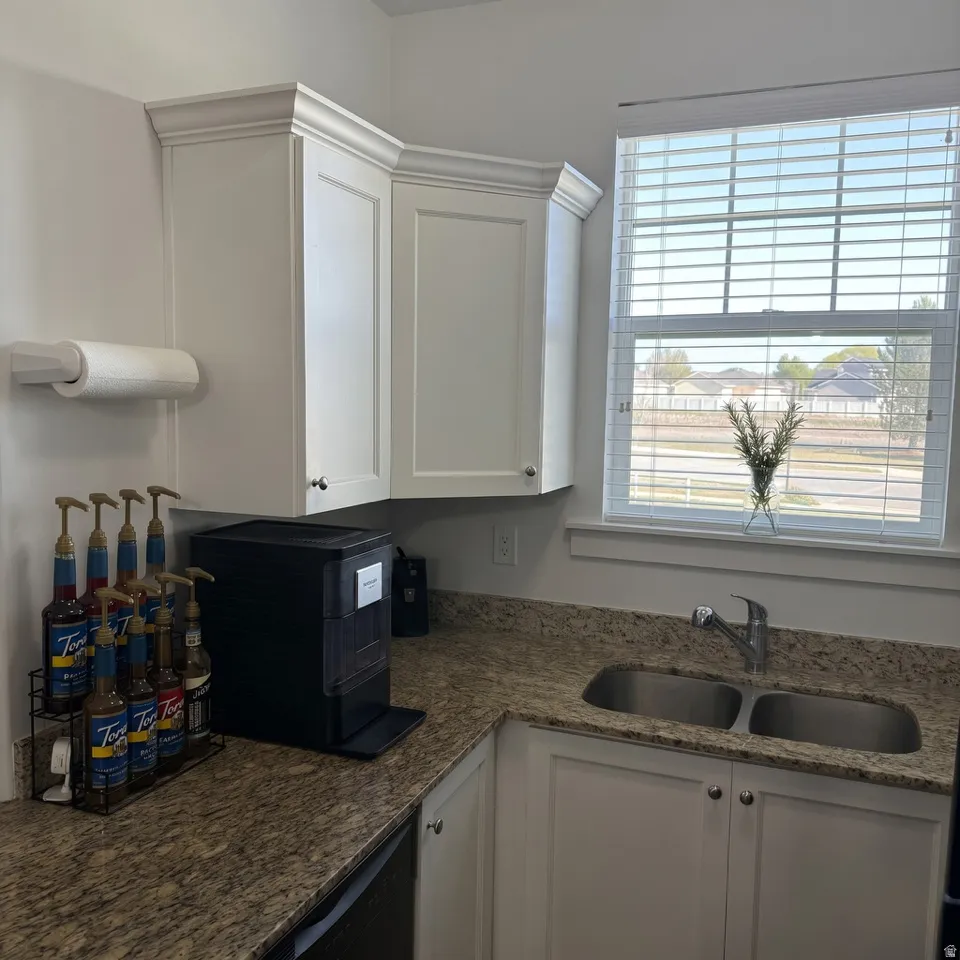 Kitchen with white cabinetry and dark stone counters