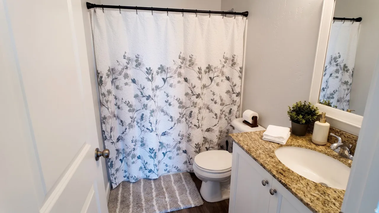 Full bathroom with vanity, a shower with curtain, and dark wood-style floors