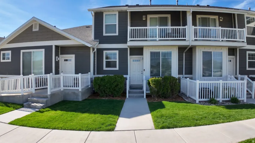 View of front of property featuring a front lawn and a shingled roof