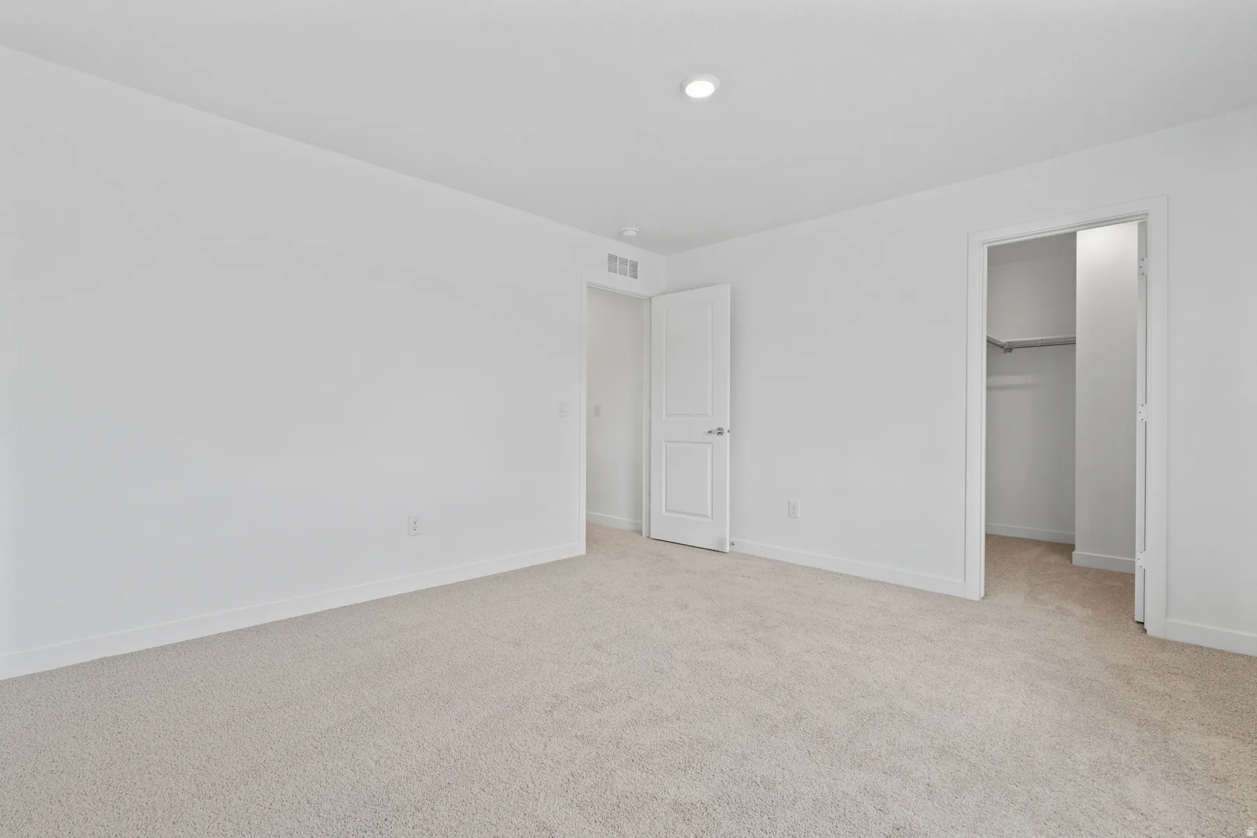 Spacious room featuring neutral carpeting, white walls, recessed lighting, and white trim