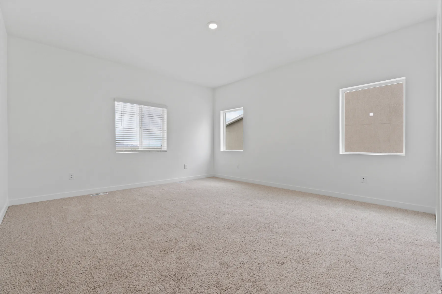 Neutral-toned carpeting paired with white walls, baseboards, and a recessed ceiling light fixture