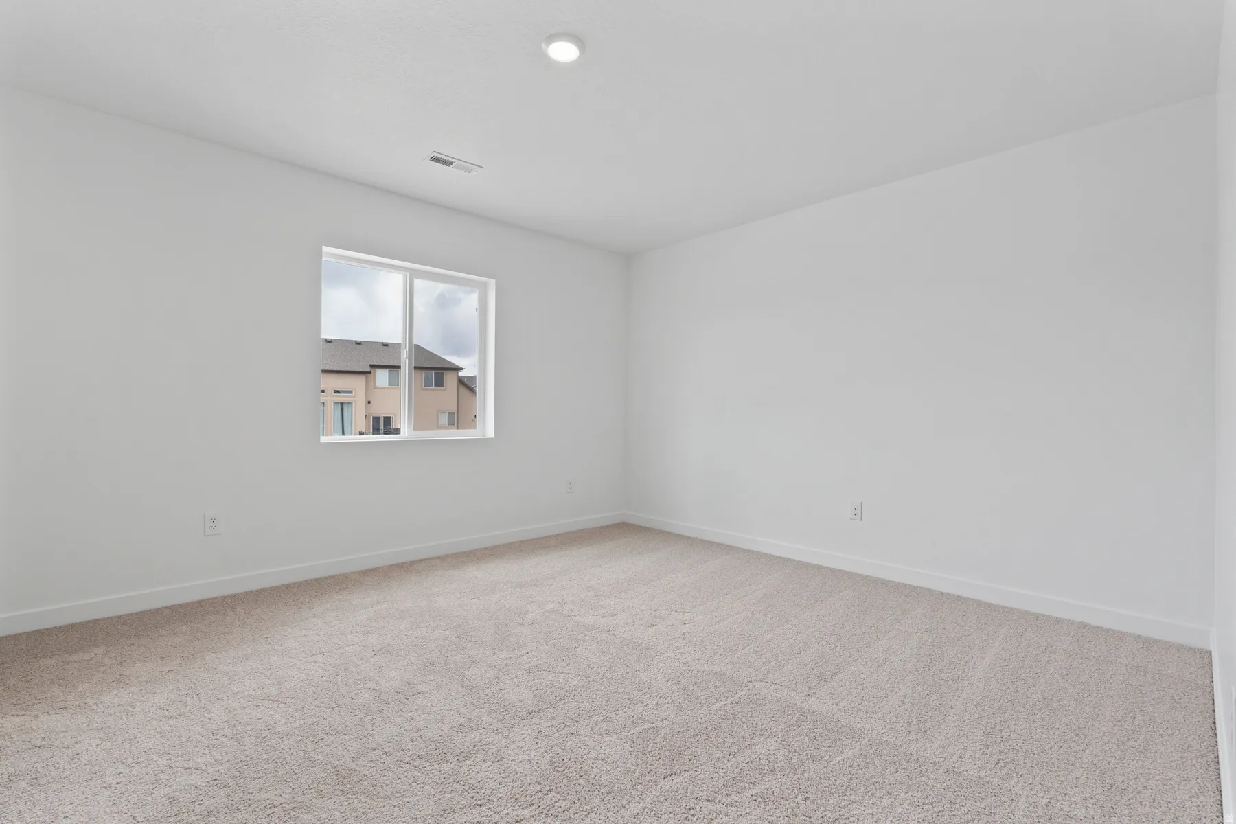 Neutral tone wall color, recessed ceiling lighting, light-toned carpet, and a window providing natural light