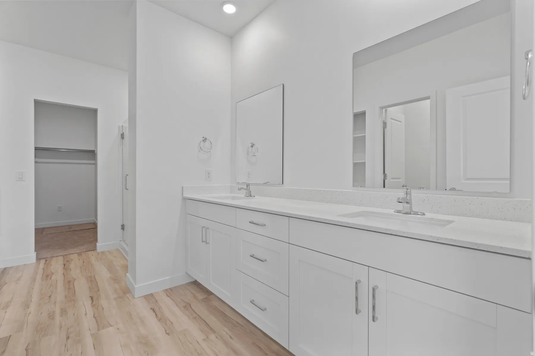 Contemporary bathroom featuring a double vanity with white cabinetry, integrated sinks, and light-toned countertops
