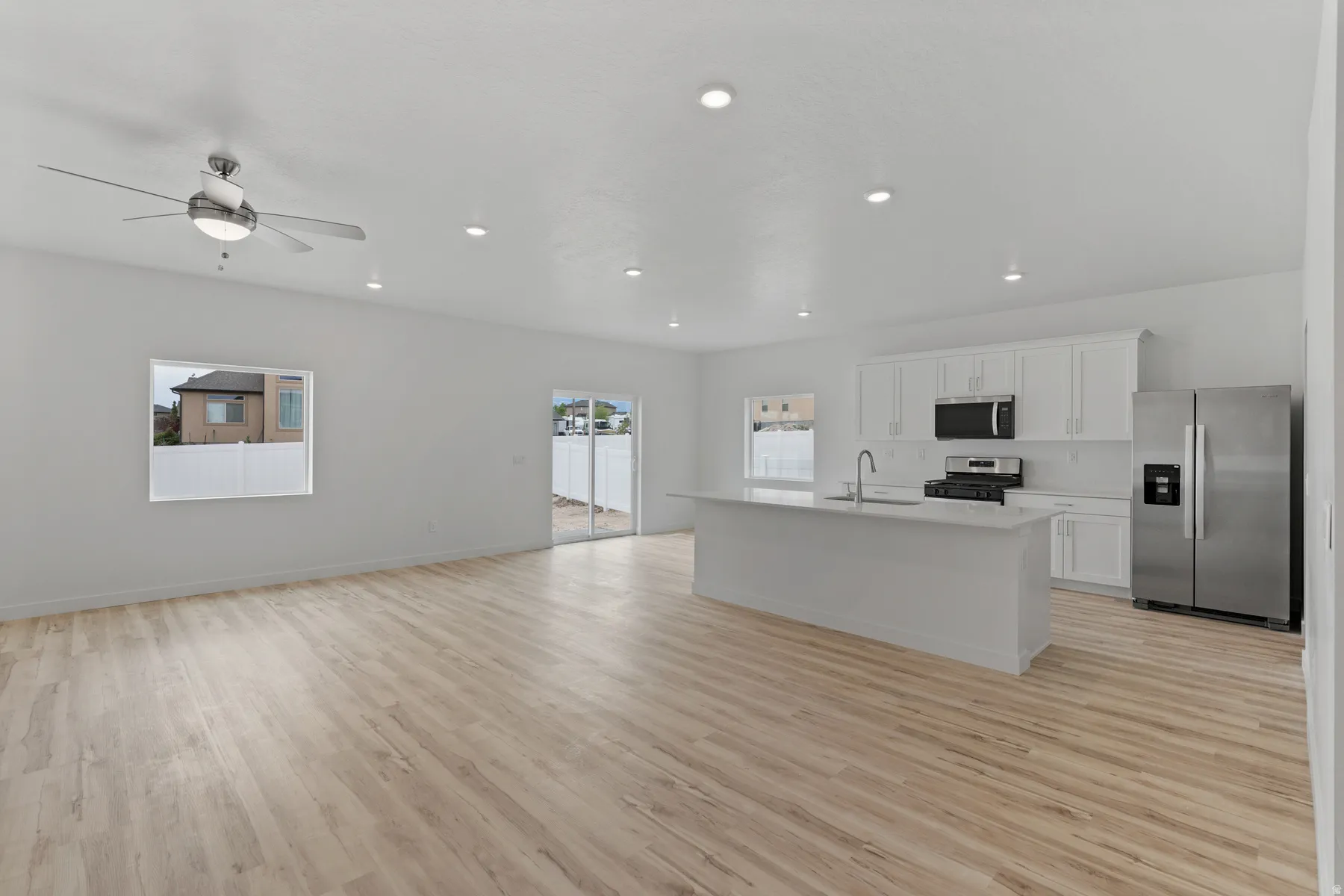 Open concept living area featuring light wood-finish flooring, recessed lighting, and a ceiling fan