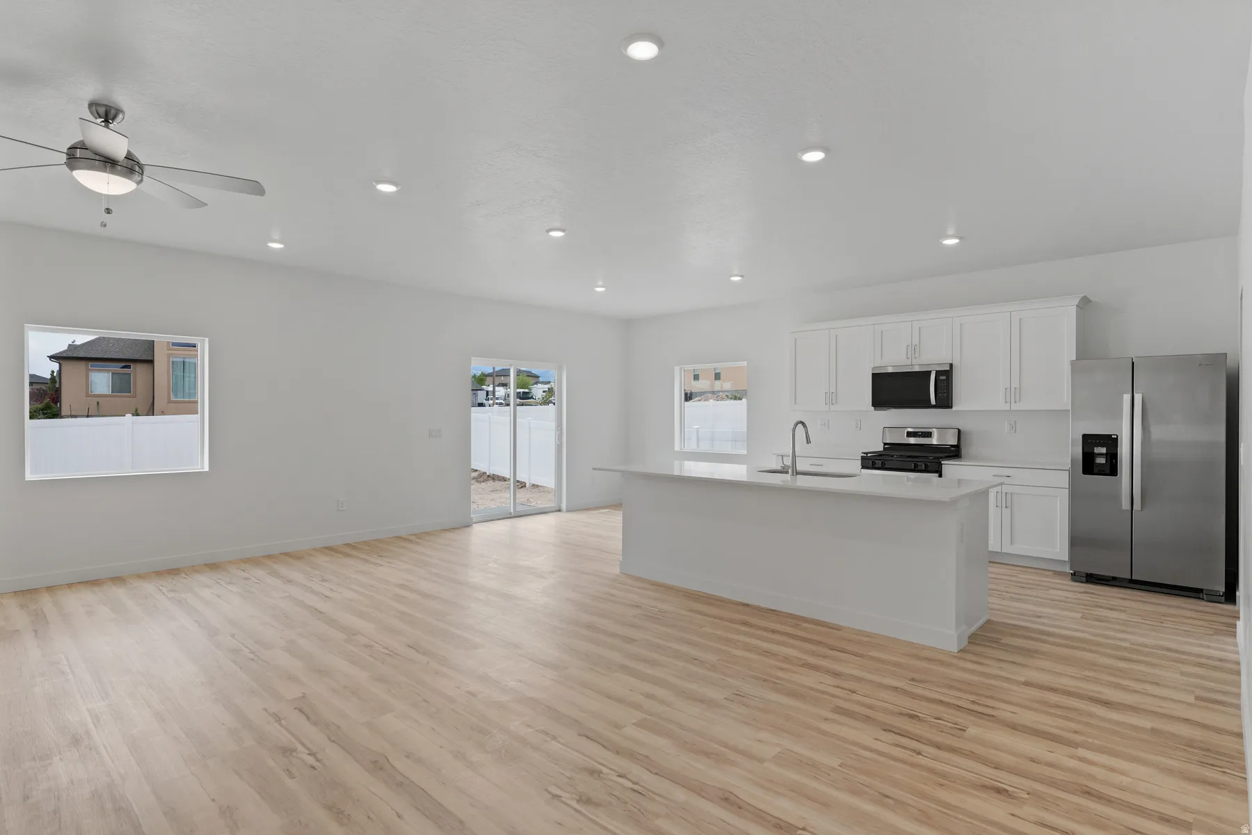 Open-concept living space featuring wood-finish flooring, recessed lighting, and a ceiling fan with integrated illumination