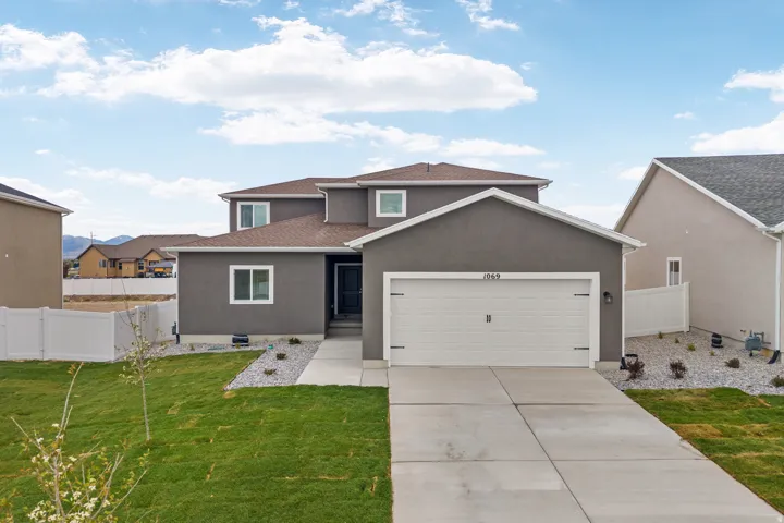 Contemporary two-story stucco exterior featuring a two-car garage, a concrete driveway, and a welcoming front walkway