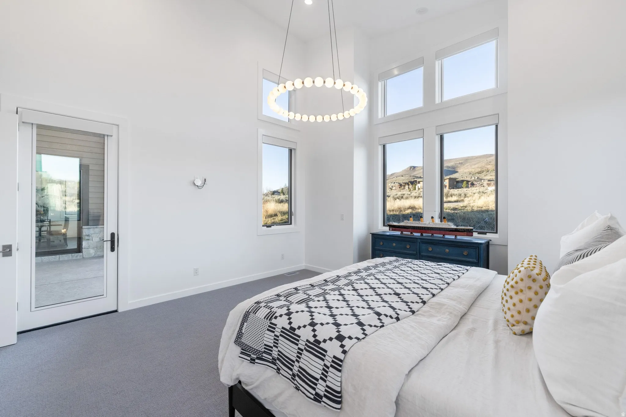 Bedroom with a high ceiling, dark colored carpet, and access to exterior