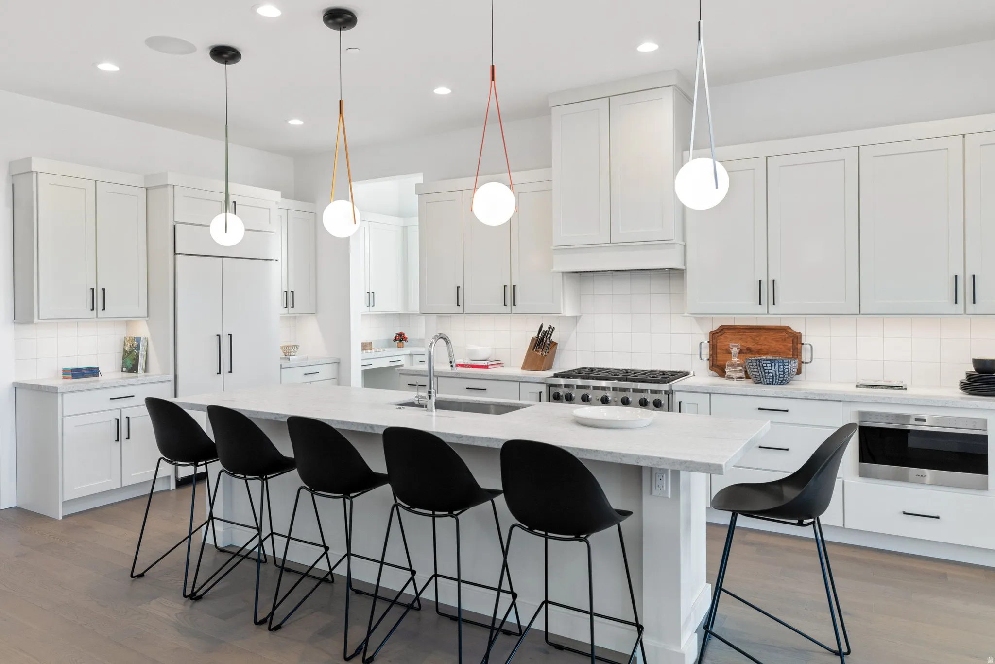 Kitchen featuring a breakfast bar, dark wood finished floors, hanging light fixtures, and a center island with sink