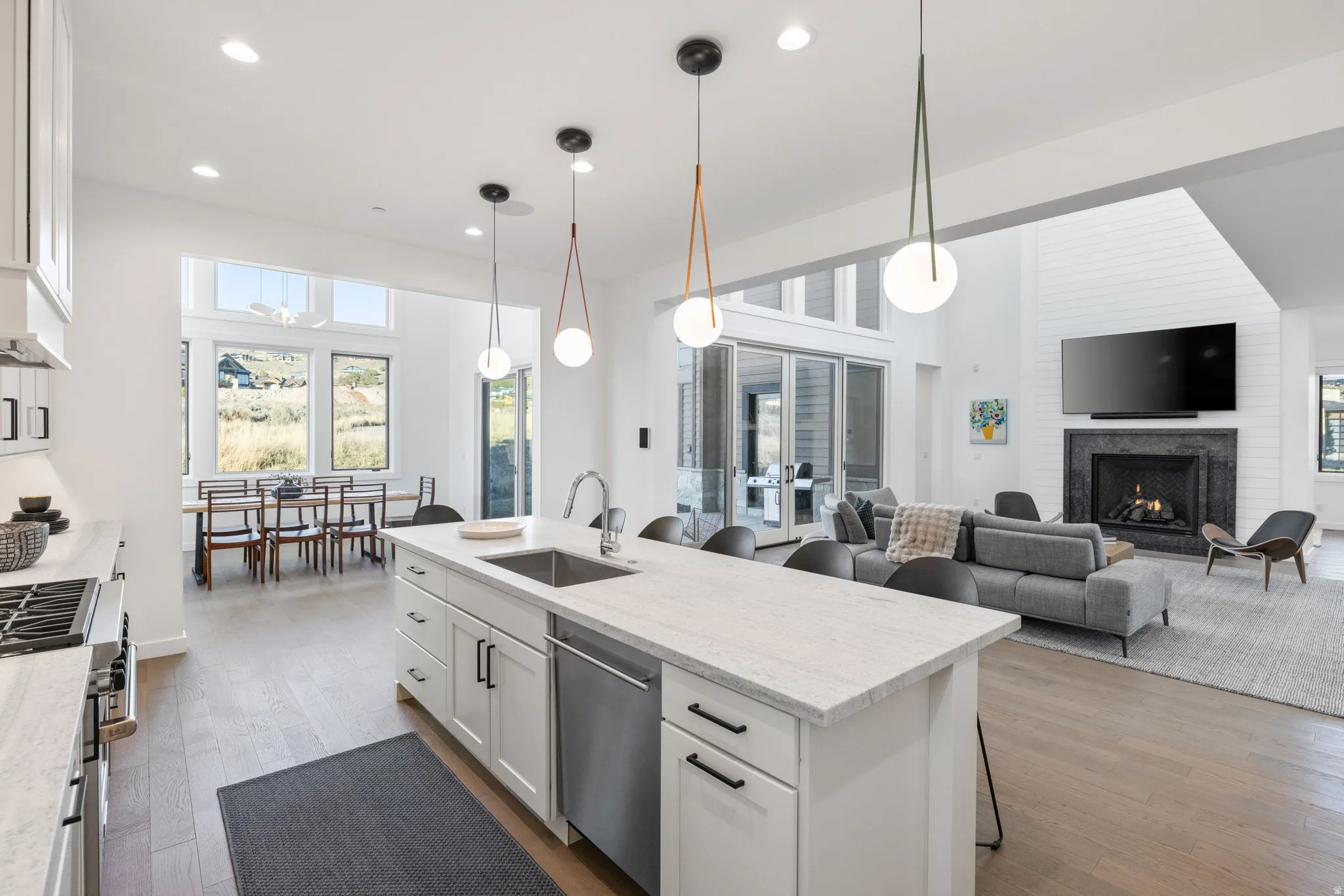 Kitchen featuring a breakfast bar area, white cabinetry, light wood finished floors, open floor plan, and light stone countertops