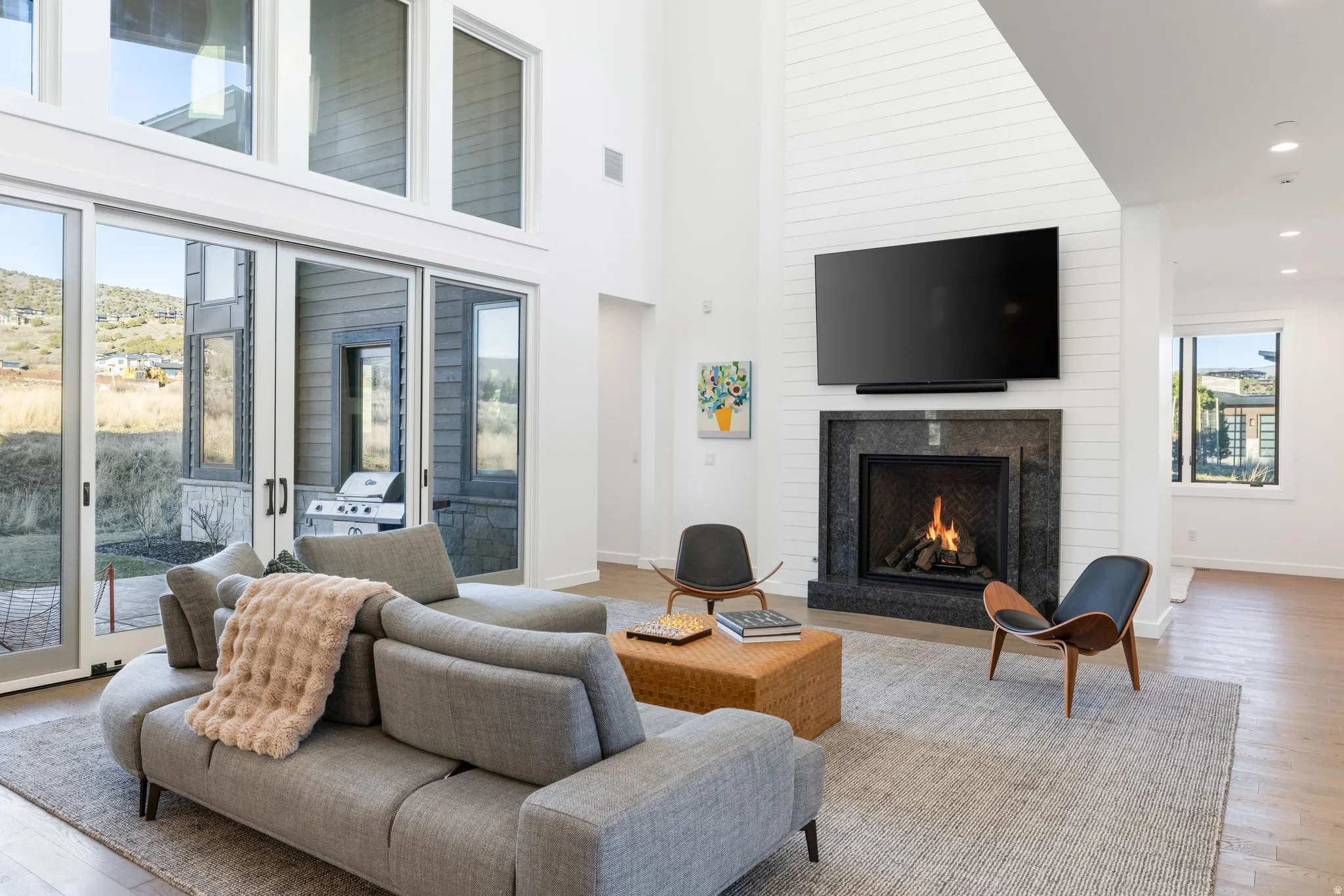 Living room featuring light wood-style floors, a fireplace, a high ceiling, and recessed lighting