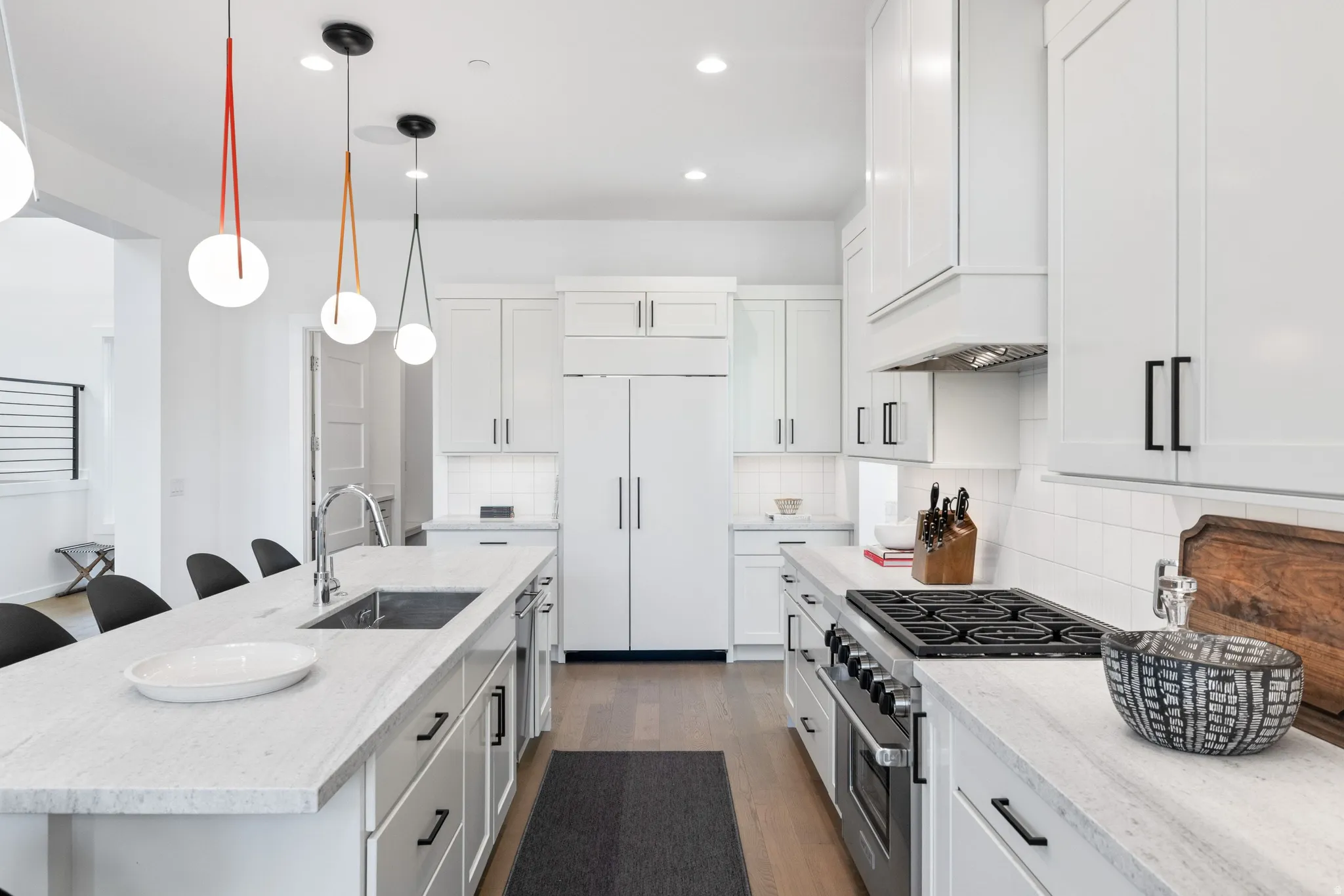 Kitchen featuring a kitchen breakfast bar, stainless steel gas stove, light stone countertops, dark wood finished floors, and a kitchen island with sink