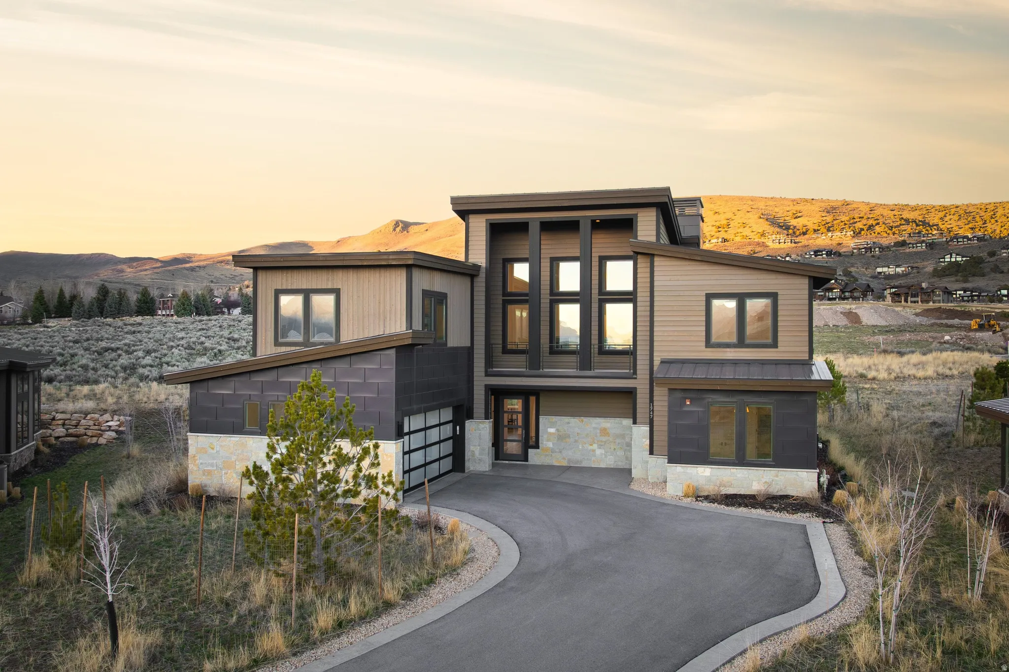 Modern home featuring stone siding, a mountain view, and asphalt driveway
