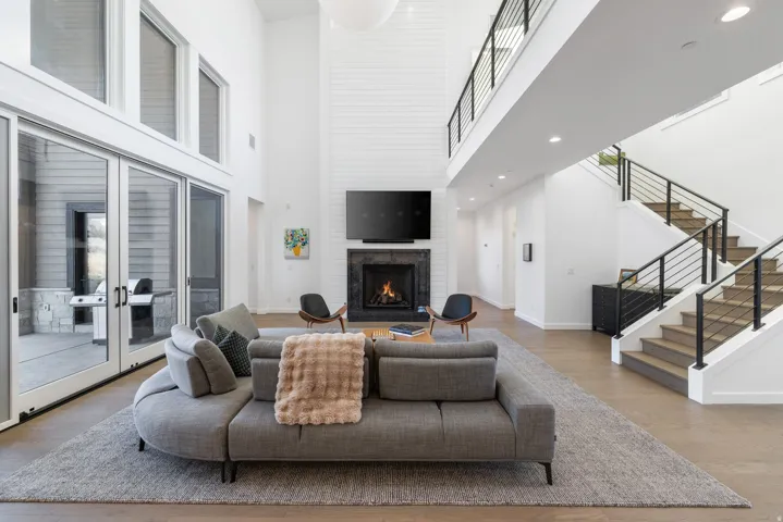 Living area with a brick fireplace, a high ceiling, wood finished floors, and recessed lighting