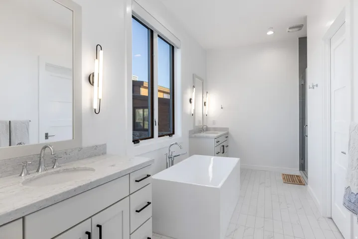 Bathroom featuring two vanities, a freestanding bath, a stall shower, and recessed lighting