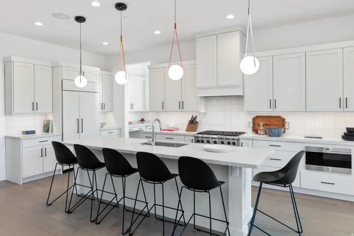 Kitchen featuring a breakfast bar, dark wood finished floors, hanging light fixtures, and a center island with sink