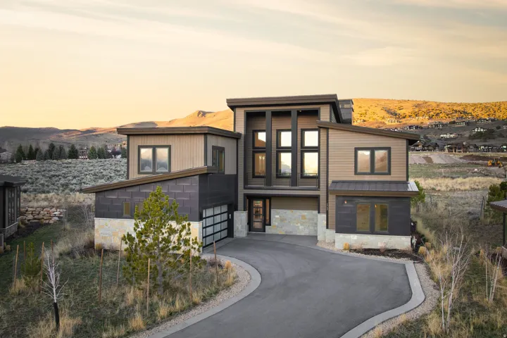 Modern home featuring stone siding, a mountain view, and asphalt driveway