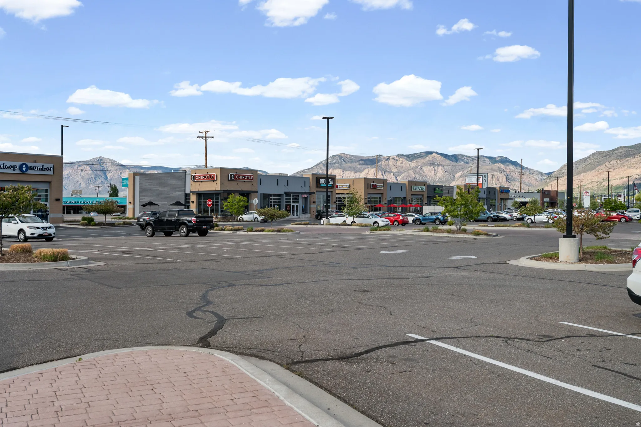 View of asphalt street with curbs, sidewalks, street lights, and a mountain view
