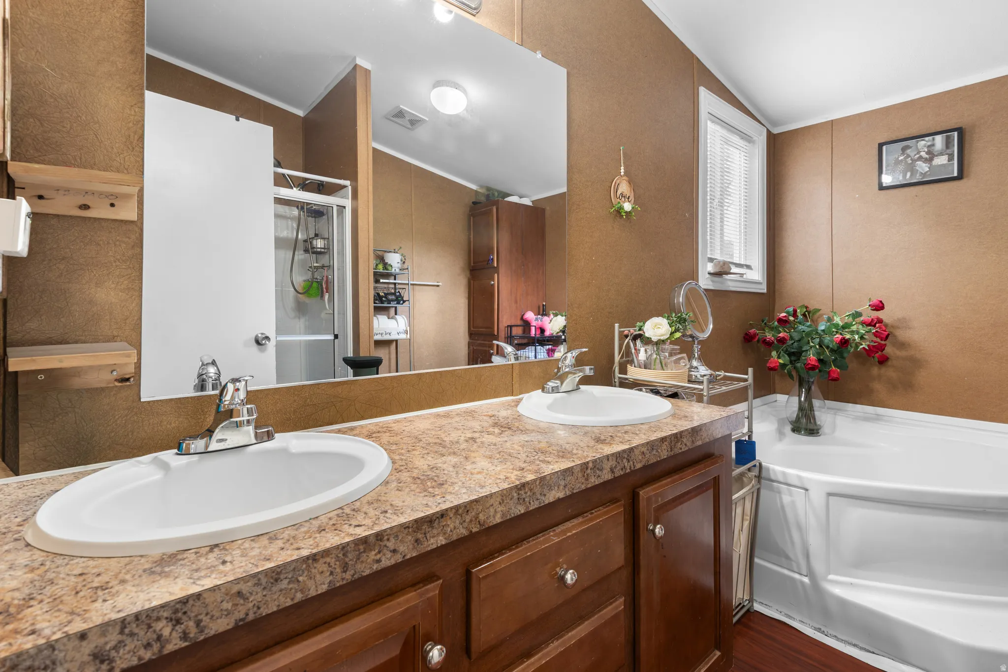 Bathroom featuring a shower stall, double vanity, a bath, crown molding, and a textured wall