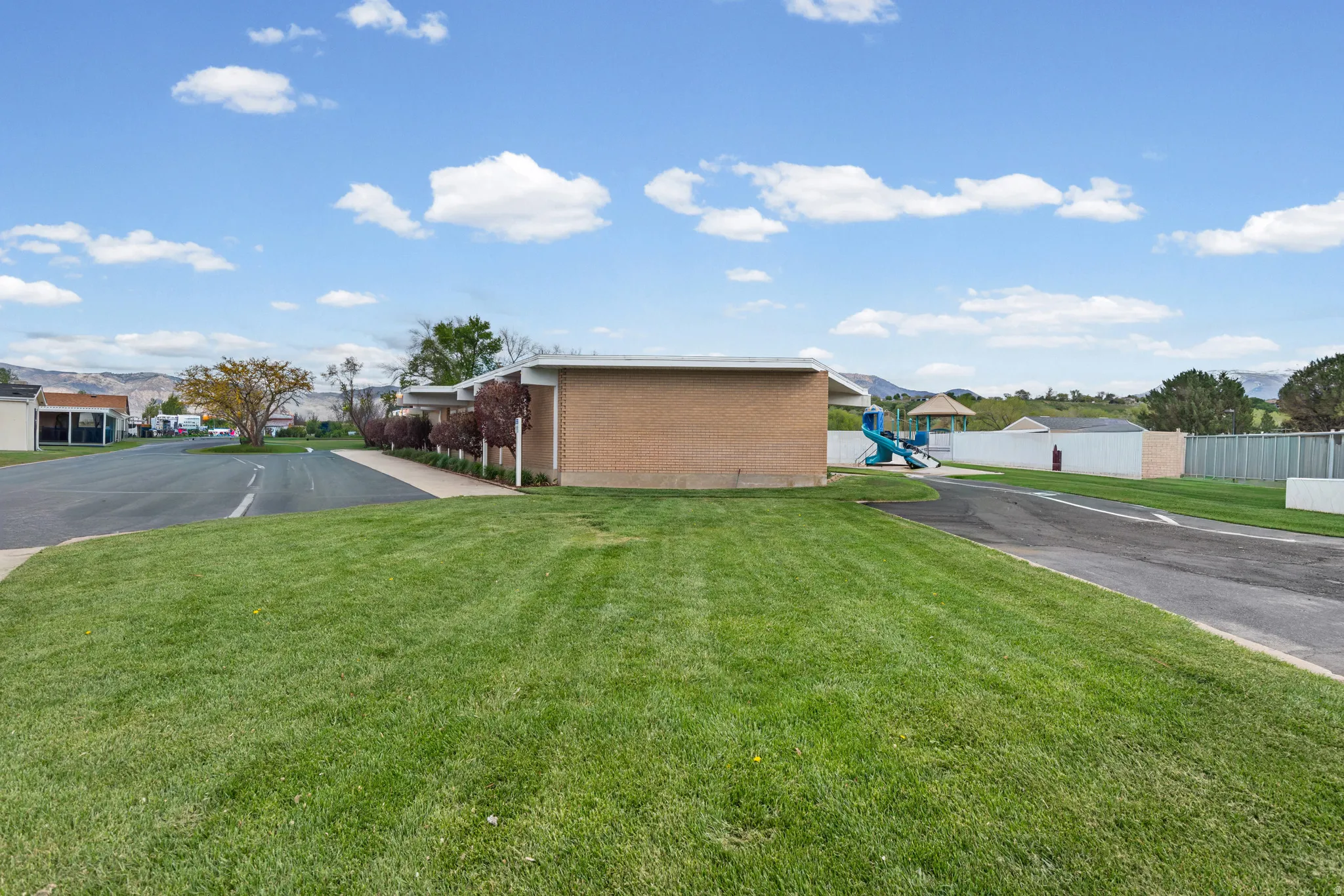 View of property exterior with brick siding, a residential view, a lawn, and a playground