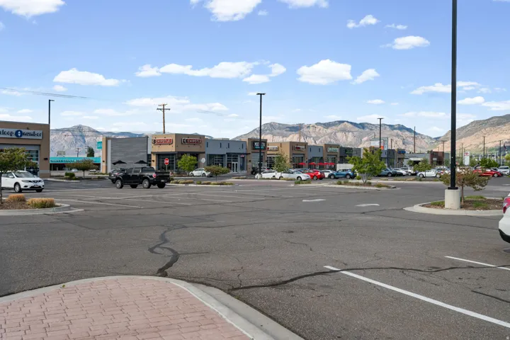 View of asphalt street with curbs, sidewalks, street lights, and a mountain view