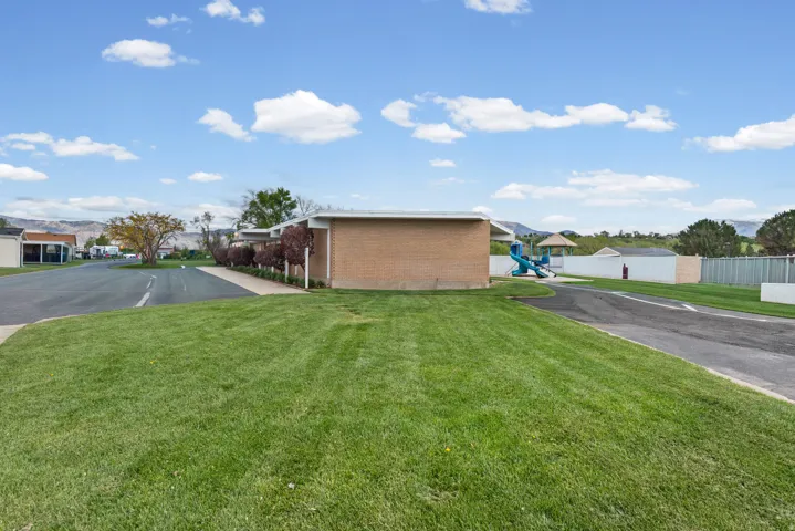 View of property exterior with brick siding, a residential view, a lawn, and a playground