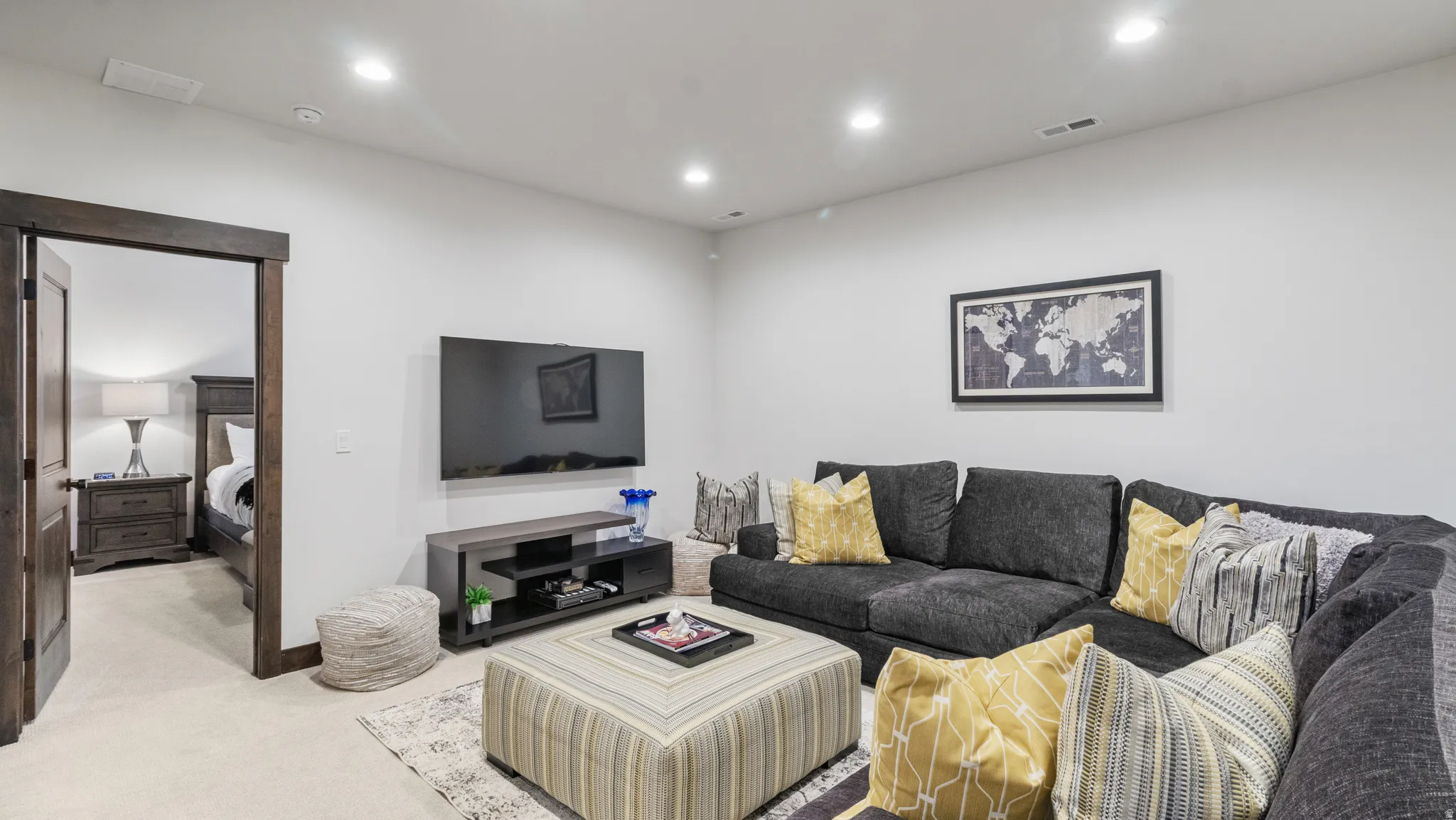 Living area with light carpet and recessed lighting