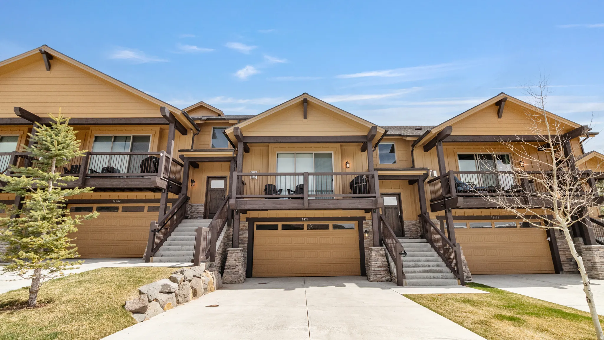 Craftsman-style house featuring a garage, stone siding, and driveway