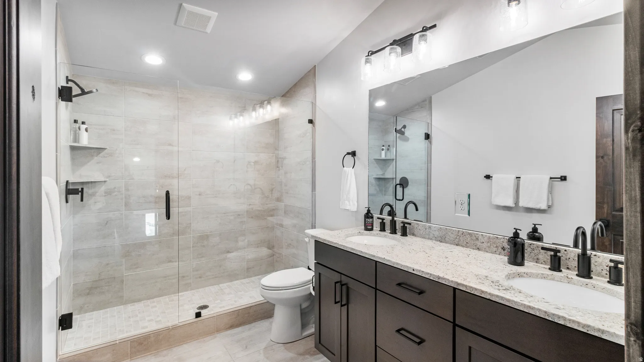 Bathroom with double vanity, a stall shower, and recessed lighting