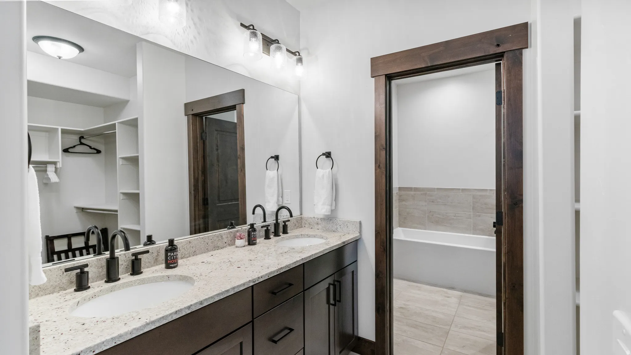 Bathroom with double vanity, a bath, and light tile patterned floors