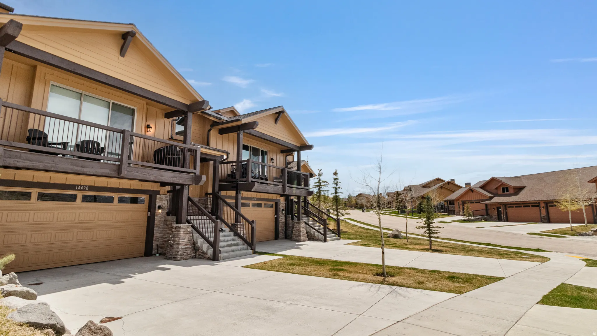 View of front of house with stone siding, a residential view, driveway, and an attached garage