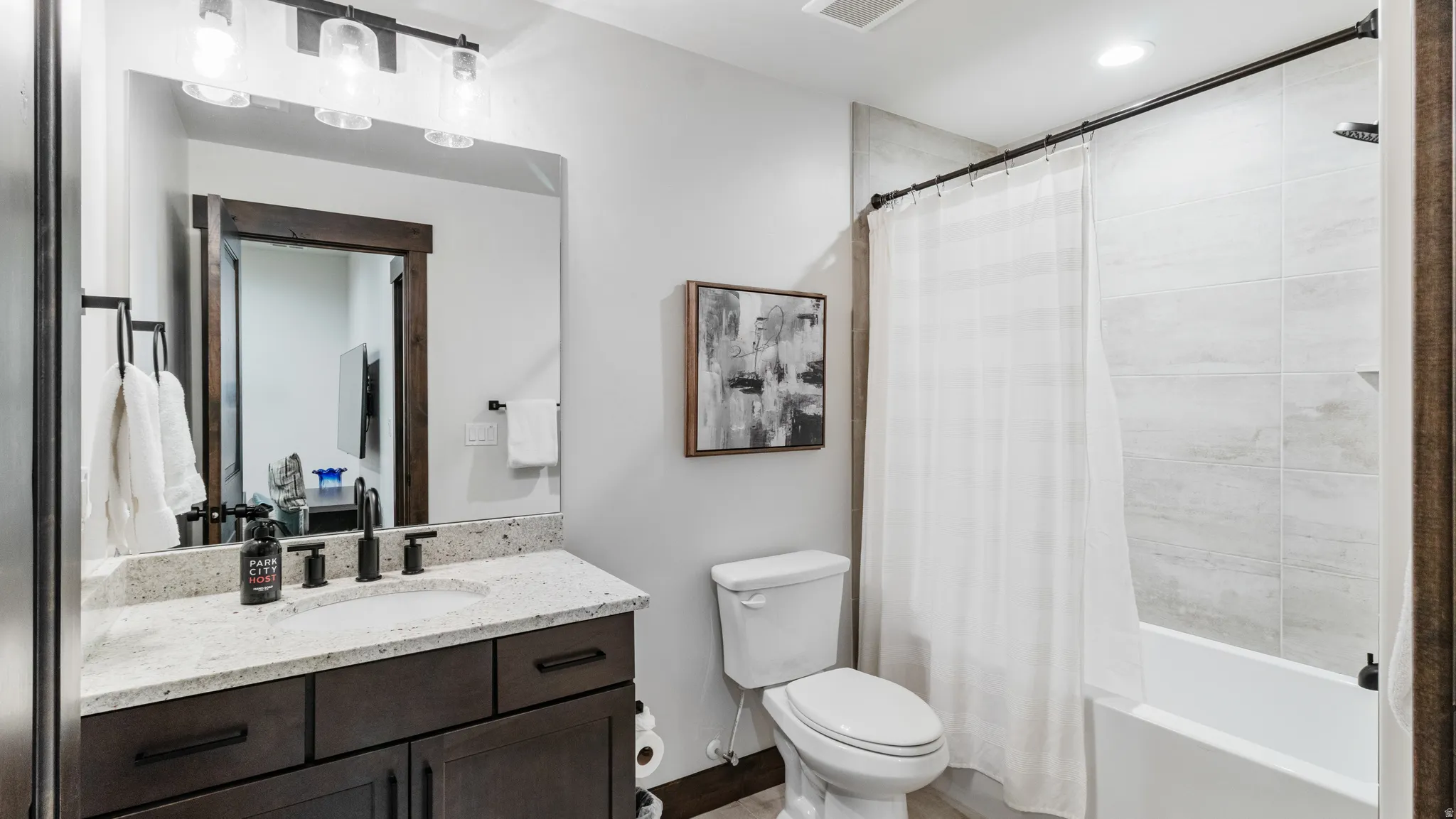 Bathroom featuring vanity, shower / tub combo with curtain, and recessed lighting