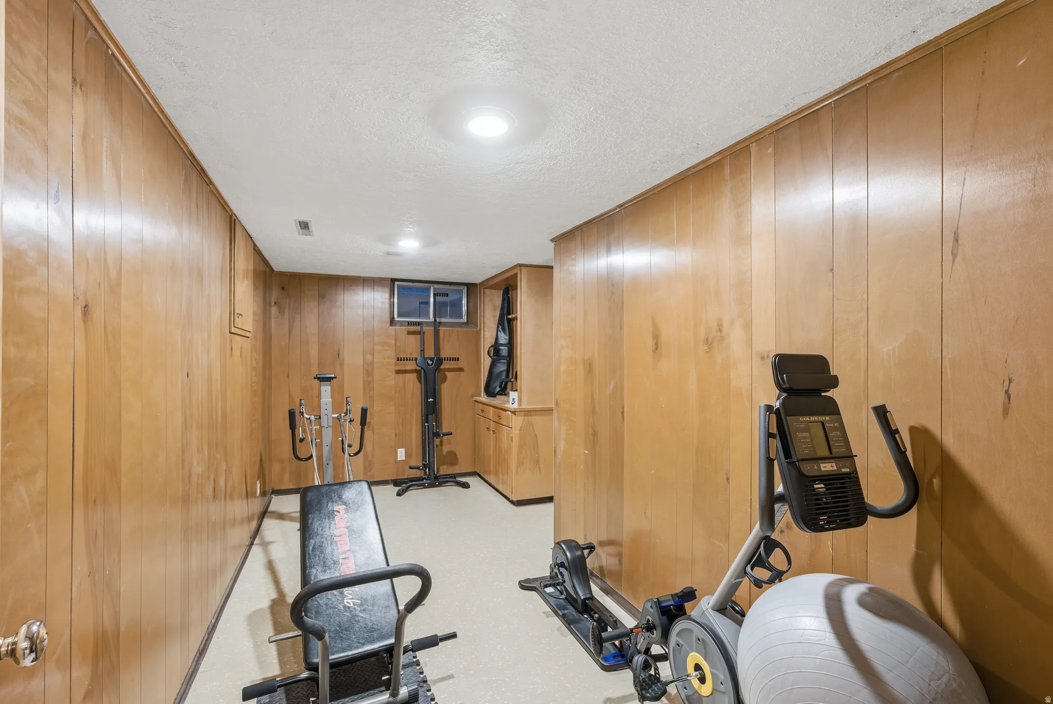 Workout room featuring a textured ceiling and wooden walls