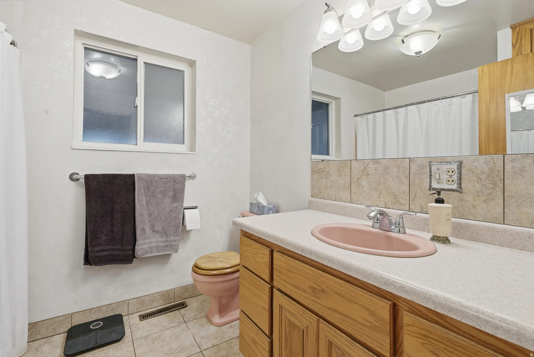 Full bath with curtained shower, vanity, and light tile patterned floors