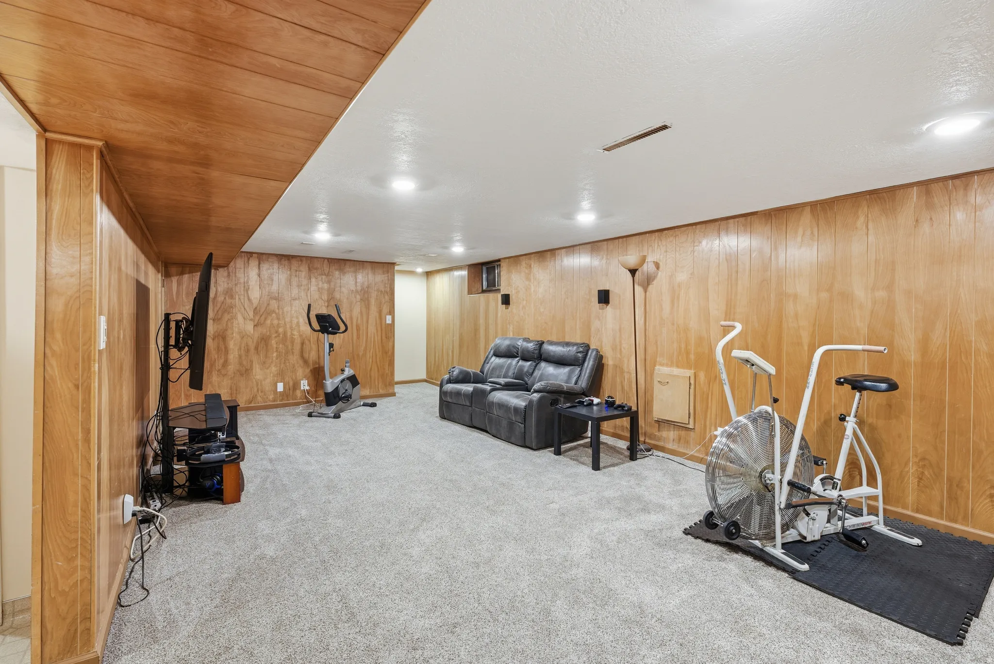 Workout room featuring light carpet and wooden walls