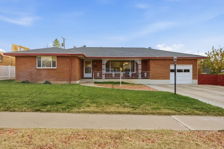 Ranch-style home featuring brick siding, roof with shingles, an attached garage, concrete driveway, and a porch