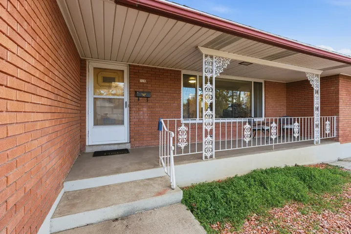 Doorway to property with covered porch and brick siding