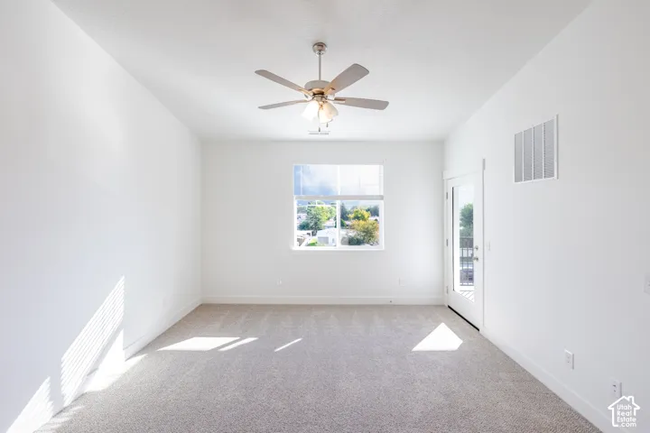 Neutral-toned carpeting, ceiling fan with integrated lighting, single-pane window, and exterior door with glass insert