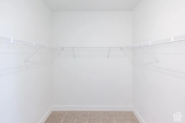 Neutral-toned carpeting and white wire shelving mounted across three walls